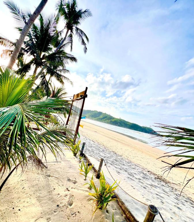 A palm-lined beach path at The Sanctuary looking toward an El Nido headland